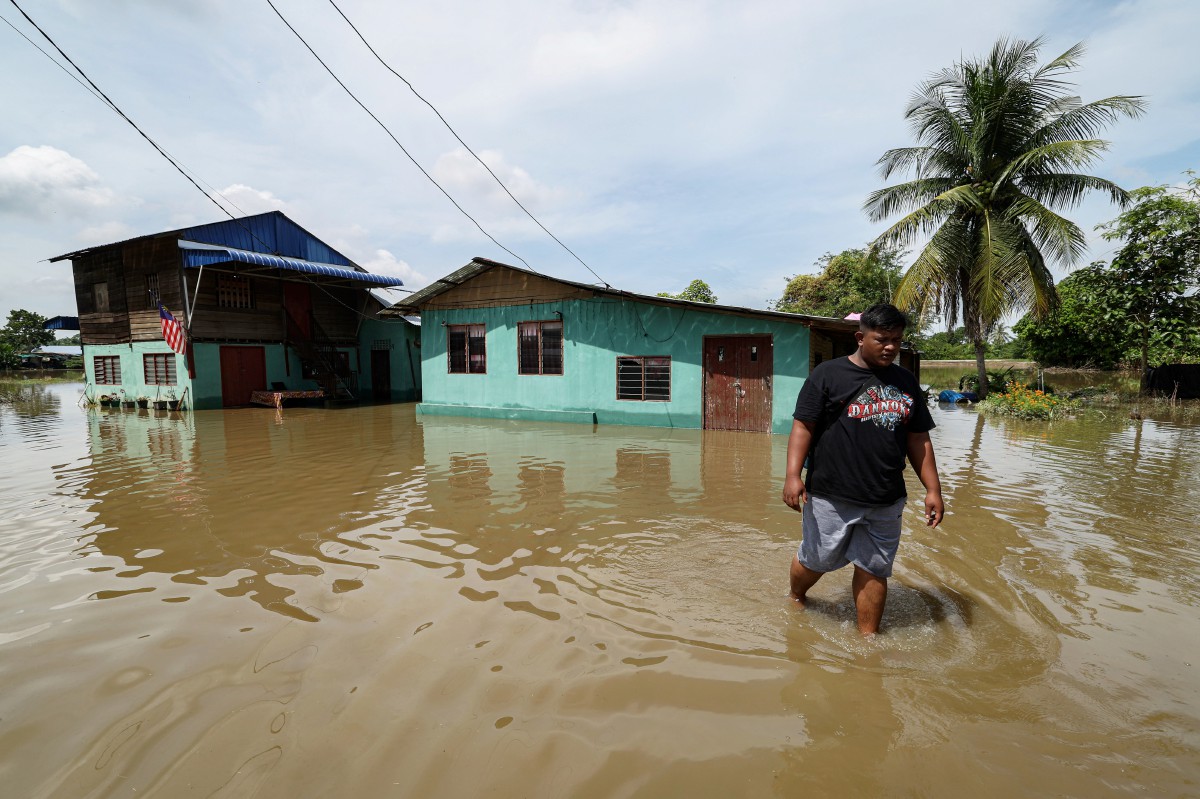 Penduduk kampung Muhammad Aminzi Adnan meninjau kawasan rumahnya yang dinaiki air susulan hujan lebat kelmarin di Kampung Seberang Tok Do. FOTO BERNAMA