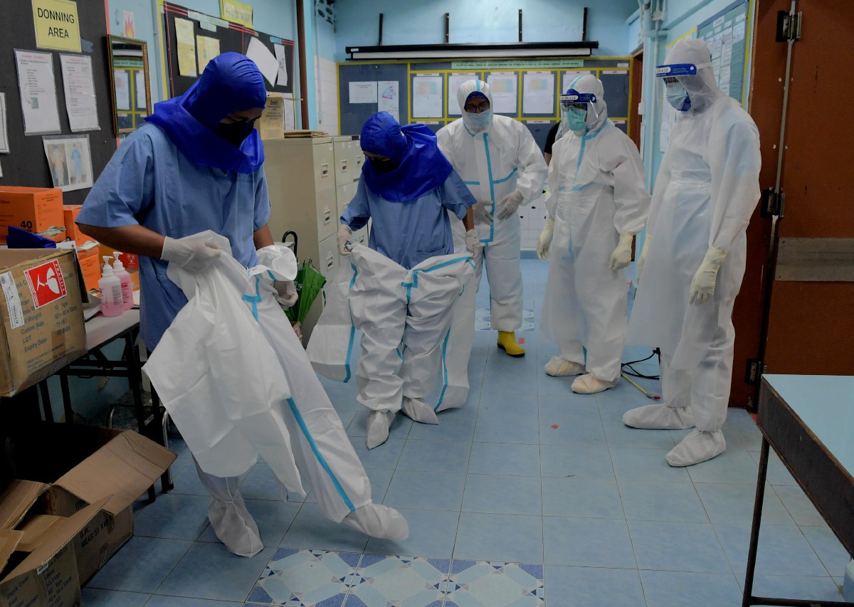Faizah (dua dari kiri) bersama rakan setugas memakai pakaian perlindungan diri (PPE) sebagai langkah keselamatan setiap kali mengendalikan jenazah pesakit Covid-19 ketika ditemui di Jabatan Perubatan Forensik Hospital Sultanah Johor Bahru (HSA). FOTO BERNAMA