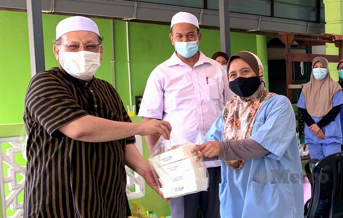 Amar Nik Abdullah (kiri) menyampaikan sumbangan makanan kepada Pegawai Perubatan Dr Suhaila Aliman yang bertugas di Taman Kurnia Jaya dekat Pengkalan Chepa yang dikenakan Perintah Kawalan Pergerakan Diperketatkan (PKPD) mulai 9 hingga 22 Julai ini. FOTO BERNAMA