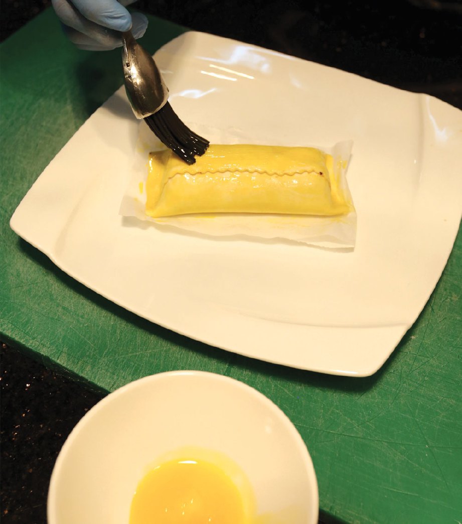 4. SAPUKAN telur kuning di atasnya supaya pastri melekat.