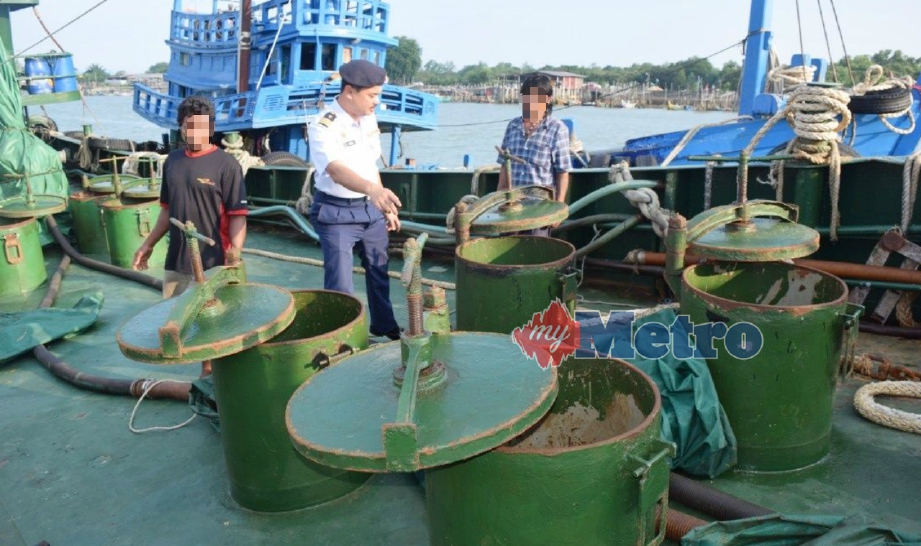 MUHAMMAD Rezal (tengah) memeriksa diesel dalam satu daripada tiga kapal tangki yang ditahan kerana dipercayai terbabit dalam aktiviti penyeludupan diesel di Jeti APMM Kemaman, Chukai, semalam. FOTO Rosli Ilham.