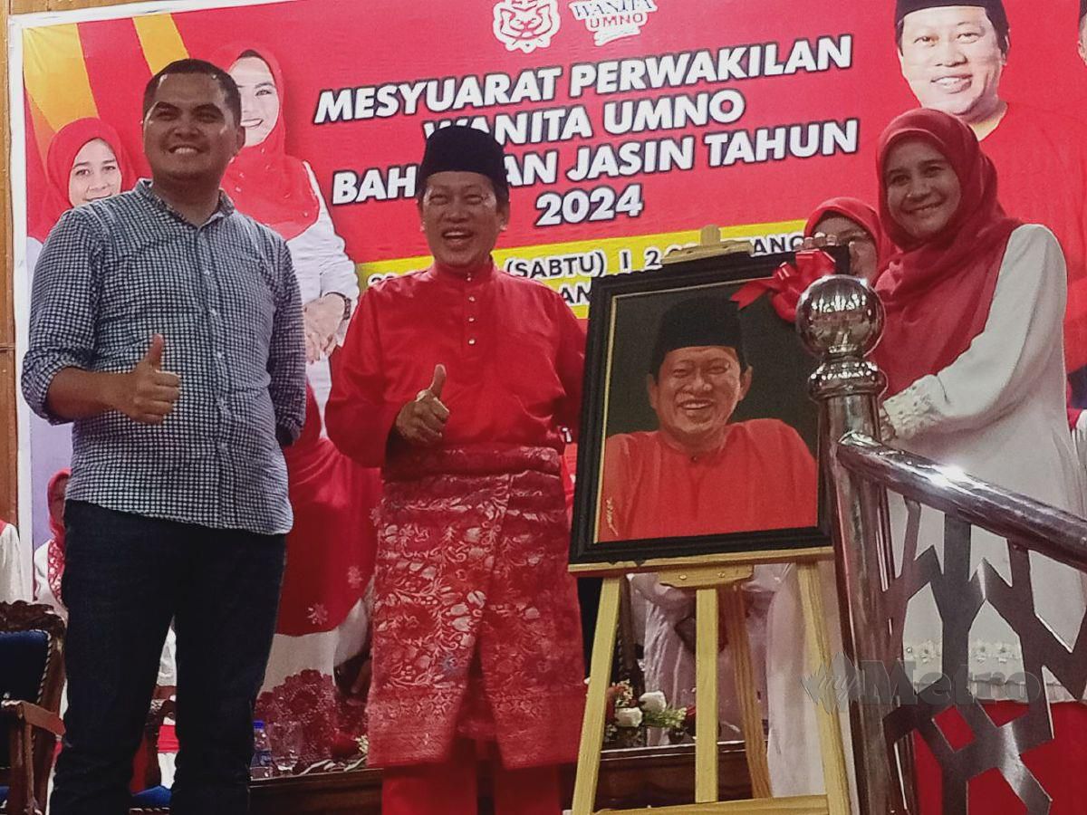 AHMAD (tengah) menerima cenderahati daripada Ketua Wanita Umno Bahagian Jasin, Siti Faizah Abd Azis sambil diperhatikan Dr Muhamad Akmal (kiri), selepas merasmikan Mesyuarat Perwakilan Wanita Umno Bahagian Jasin, hari ini. FOTO Amir Mamat