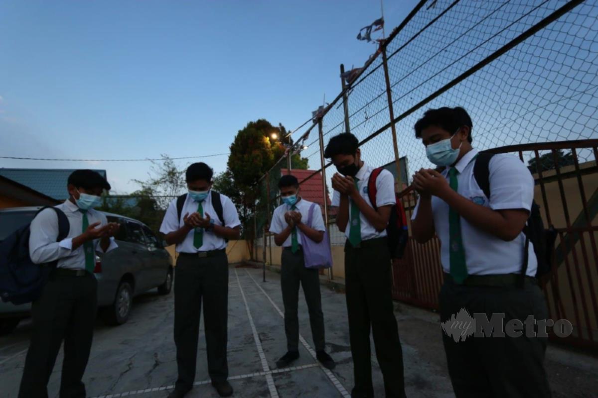 PELAJAR  Muhammad Aiman Danial Ahmad Jafri,18 (dua dari kanan) bersama rakannya mengaminkan bacaan doa sebelum memasuki sekolah untuk menduduki  SPM. FOTO Iqmal Haqim Rosman.