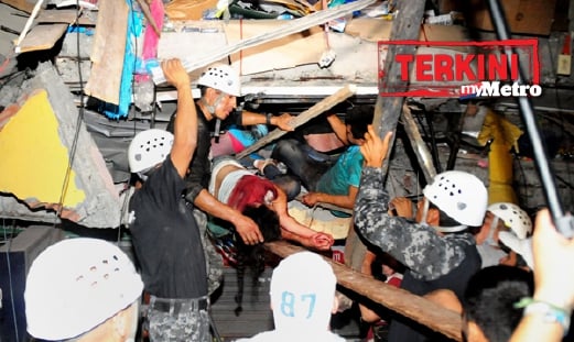 Orang ramai mengeluarkan penduduk yang terperangkap dalam runtuhan rumah di bandar Manta, Ecuador. - Foto AFP/AP