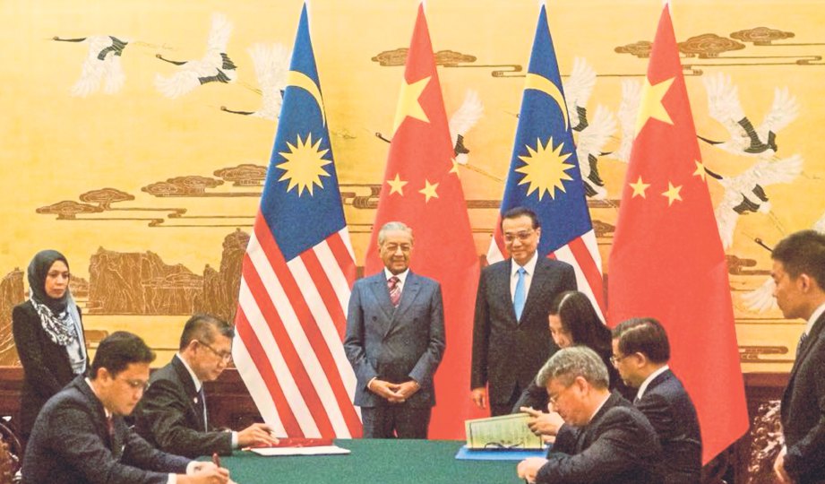 SALAHUDDIN dan Ni menandatangani perjanjian sambil disaksikan Dr Mahathir dan Li.