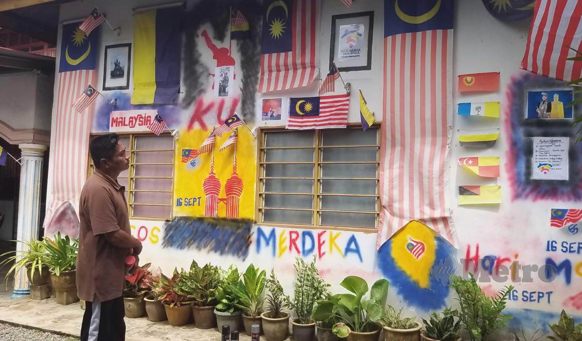 MOHAMAD Nasir meninjau dan memperkemaskan mural patriotik yang dilukis di dinding rumahnya di Banggol Sena, Chuping sempena sambutan Hari Malaysia. FOTO Aizat Sharif