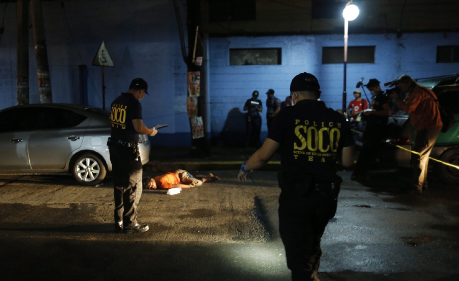 Anggota forensik Polis Kebangsaan Filipina (PNP) memeriksa mayat pengedar dadah yang mati ditembak di Manila, semalam. - Foto EPA