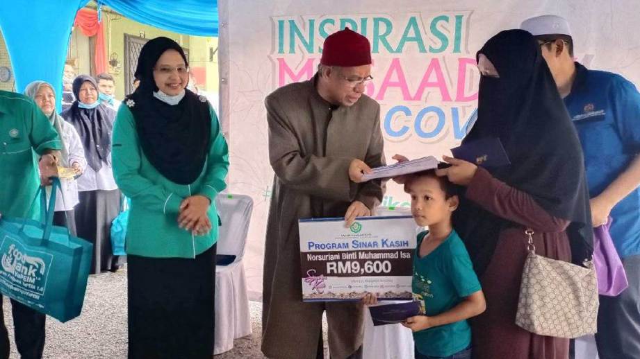 DR Zulkifli (tengah) menyerahkan sumbangan kepada penerima sempena Program Inspirasi Musaadah Covid-19 Yayasan Pembangunan Ekonomi Islam Malaysia (YaPEIM), Ar Rahnu YaPIEM Sik.FOTO Noorazura Abdul Rahman