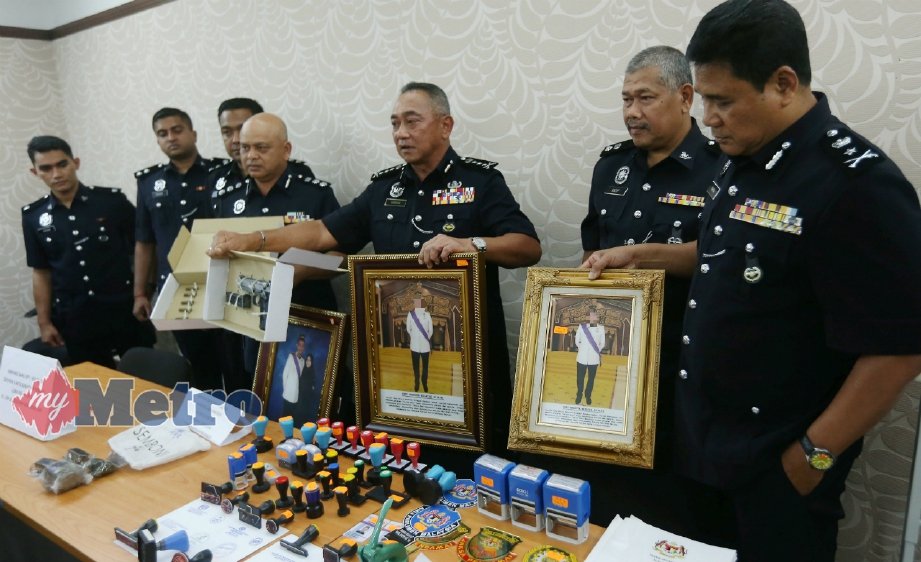 HASNAN (tiga dari kanan) menunjukkan pistol dan gambar lelaki yang aktif menjalankan kegiatan penipuan menggunakan nama Yang di-Pertuan Agong, Sultan dan Perdana Menteri pada sidang media di IPK Perak, Ipoh, hari ini. FOTO Effendy Rashid