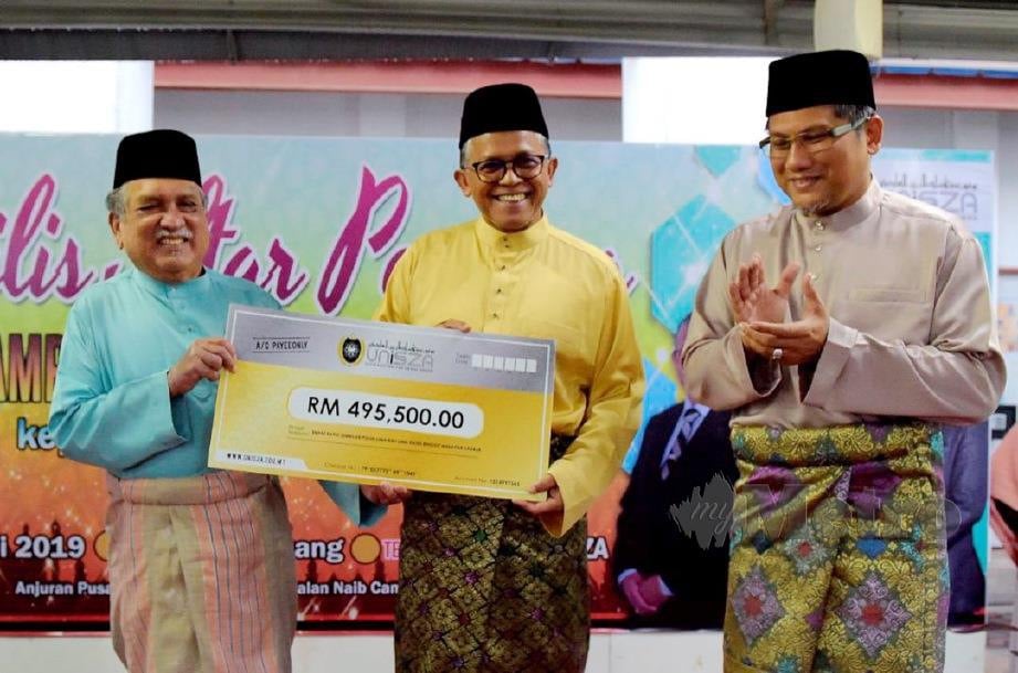HASSAN Basri (tengah) menerima replika cek berjumlah RM495,500 daripada Muhammad Nur Manuty pada Majlis Iftar Perdana, malam tadi. FOTO Mohd Aizat Shamsuddin