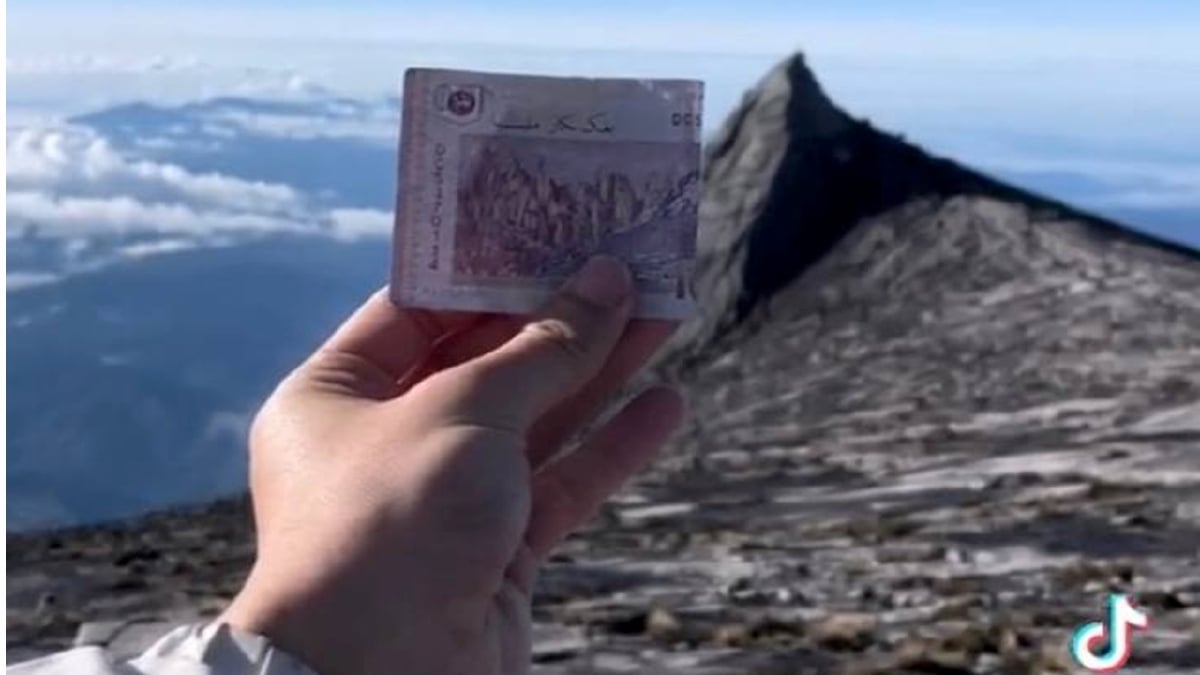 NIK Izzuddin Omary memadankan wang kertas RM100 ketika di atas Gunung Kinabalu. FOTO Ihsan Pembaca.