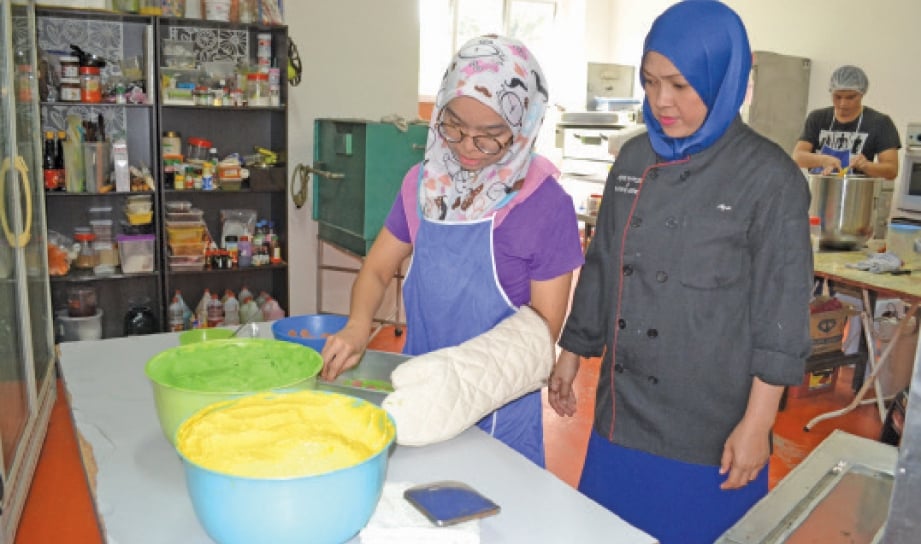 AZIE memantau pekerja membuat lapisan pada kek lapis.