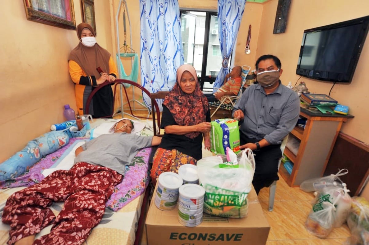 MAS Imran (kanan) menyerahkan sumbangan barangan keperluan Mariam kepada Salbiah.
