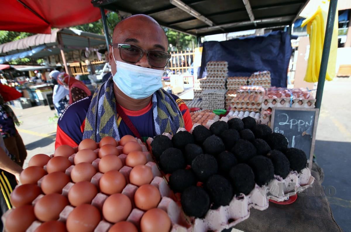 Mohamad Asri menunjukkan telur ayam dan telur masin yang dijual di Pasar pagi Kamunting. FOTO SHARUL HAFIZ ZAM