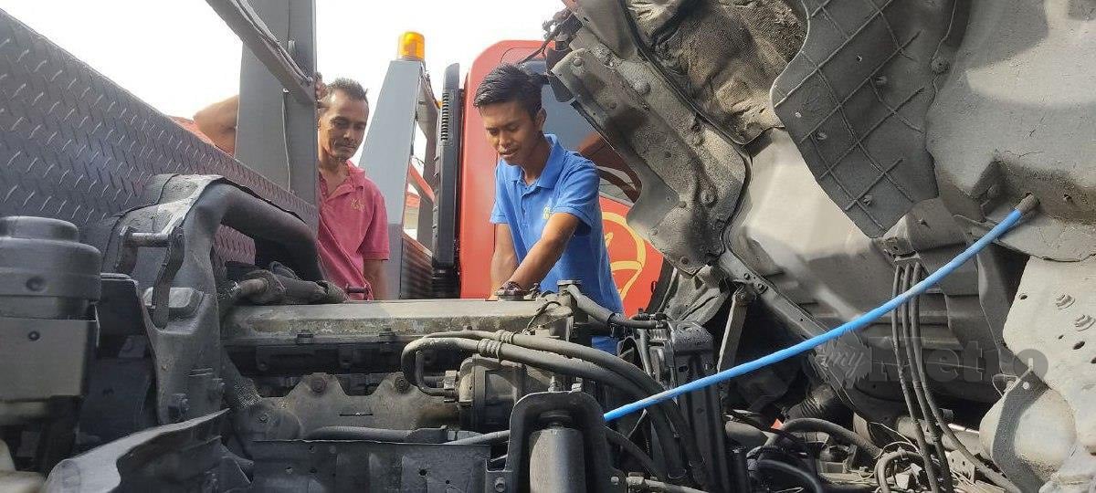 ABDUL Zaman  dan Cik Roslan memeriksa enjin kenderaan sebelum melakukan perjalanan  menarik kereta.