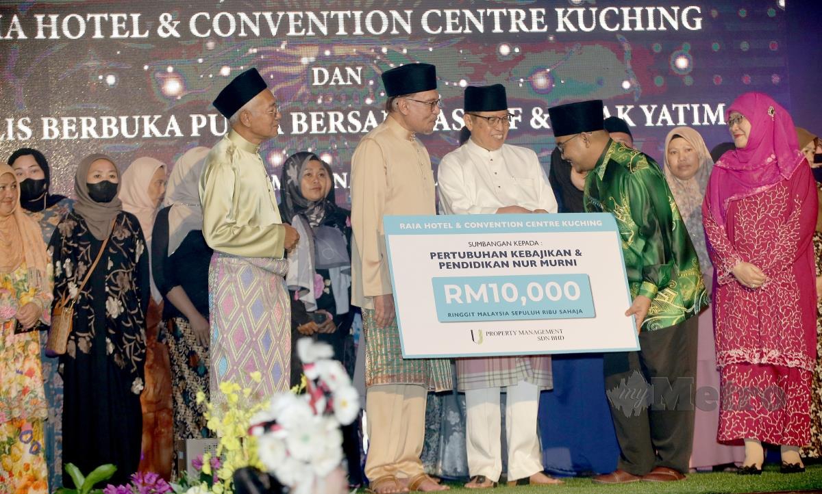 Anwar Ibrahim dan Abang Johari menyampaikan sumbangan kepada salah seorang penerima pada Perasmian Raia Hotel, Pusat Konvensyen dan Majlis Berbuka Puasa Bersama Asnaf dan Anak-Anak Yatim di Hotel Raia, Kuching. FOTO NADIM BOKHAR