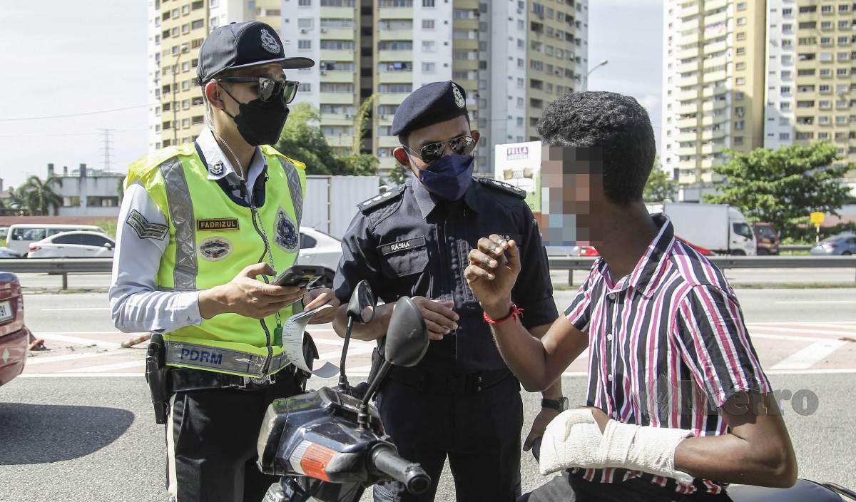 ANGGOTA polis trafik menahan seorang penunggang motosikal yang menunggang motosikal tanpa menggunakan topi keledar ketika Operasi Utama P Hailing oleh JSPT Bukit Aman di Jalan Selayang-Kuala Lumpur. FOTO Aizuddin Saad
