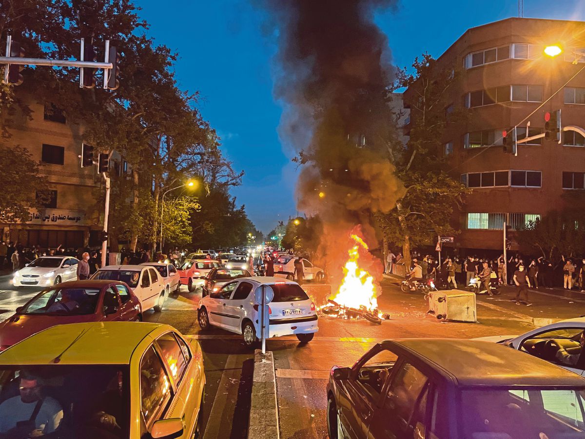 FOTO fail pada 19 September yang diperoleh AP menunjukkan motosikal polis dibakar ketika rusuhan di Tehran. FOTO AP 