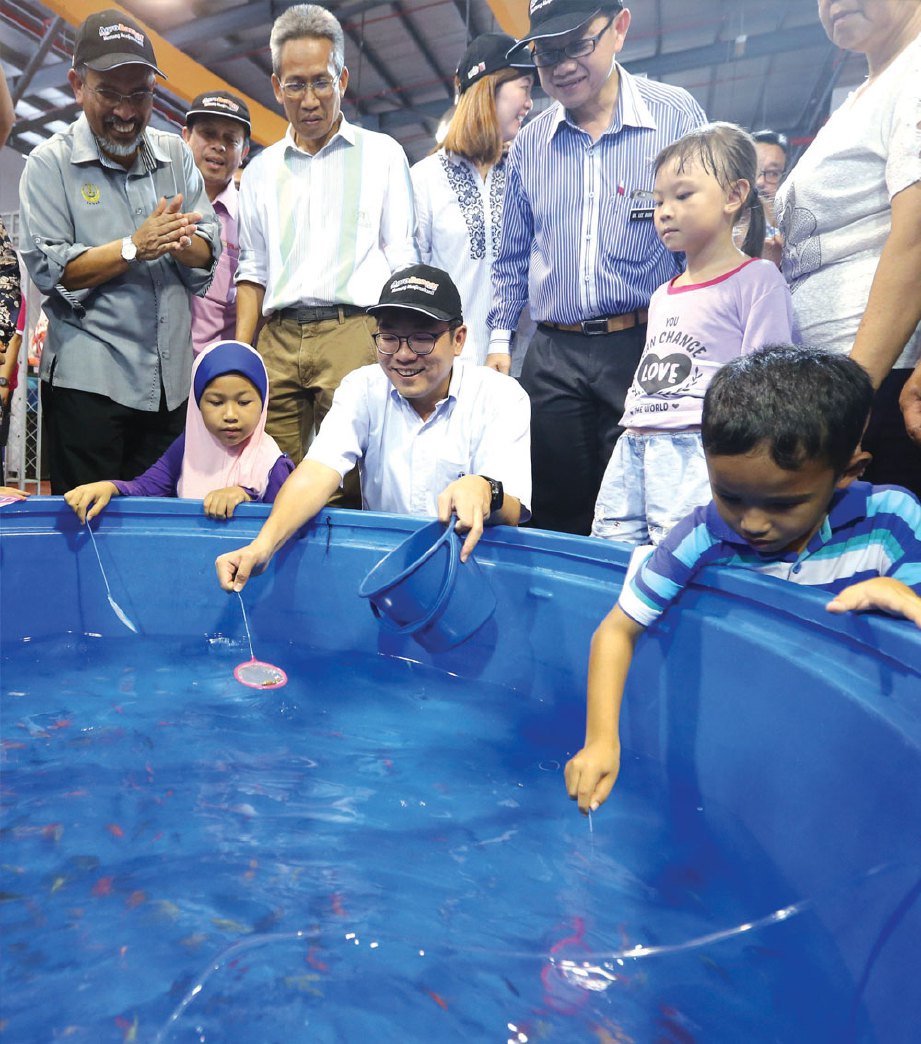 TIMBALAN Menteri Pertanian dan Industri Asas Tani Sim Tze Tzin (duduk dua dari kanan) menangkap anak ikan hiasan.