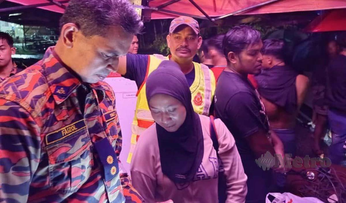 FARAH Adnan memberi informasi kepada salah seorang pegawai bomba ketika ditemui di lokasi kejadian di Kampung Petai Dusun, Baroh Pial, malam tadi. FOTO Syaherah Mustafa