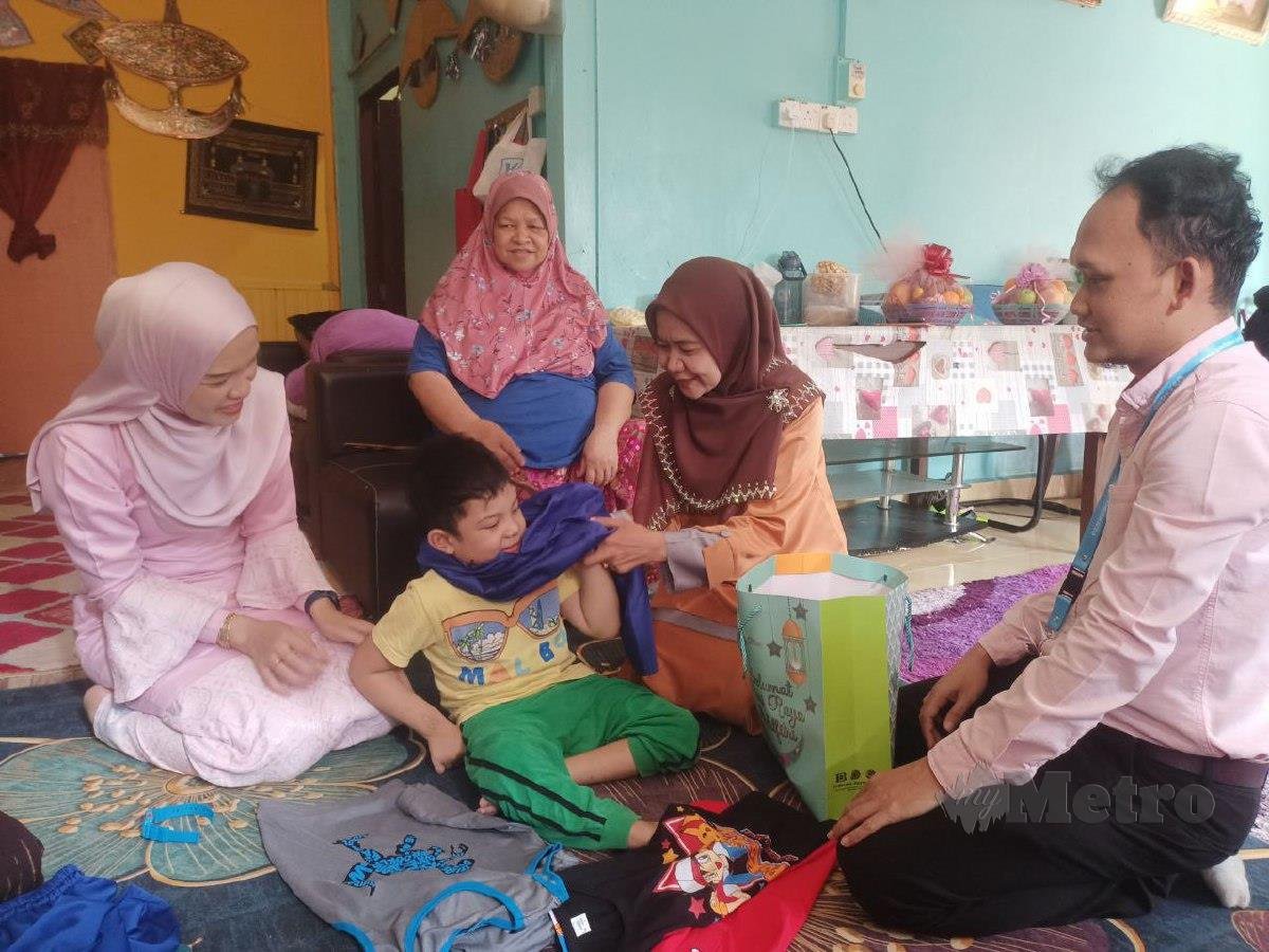 NORA memakaikan baju Melayu kepada Fariz yang kehilangan kedua ibu bapa dan adik dalam nahas jalan raya tahun lalu. FOTO Siti Rohana Idris