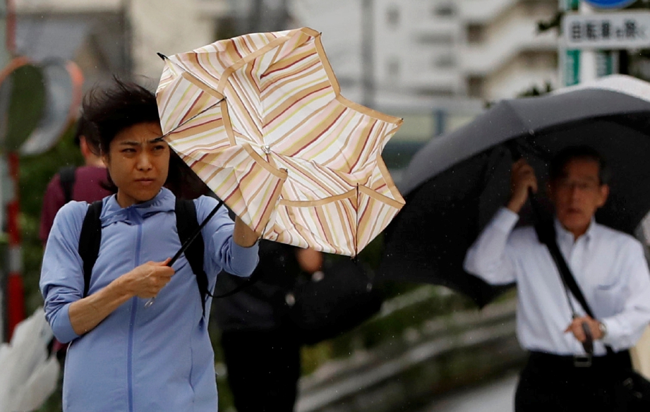 PENDUDUK terpaksa berhadapan dengan angin kencang dan hujan lebat yang melanda akibat taufan Faxai di Tokyo. FOTO: Reuters