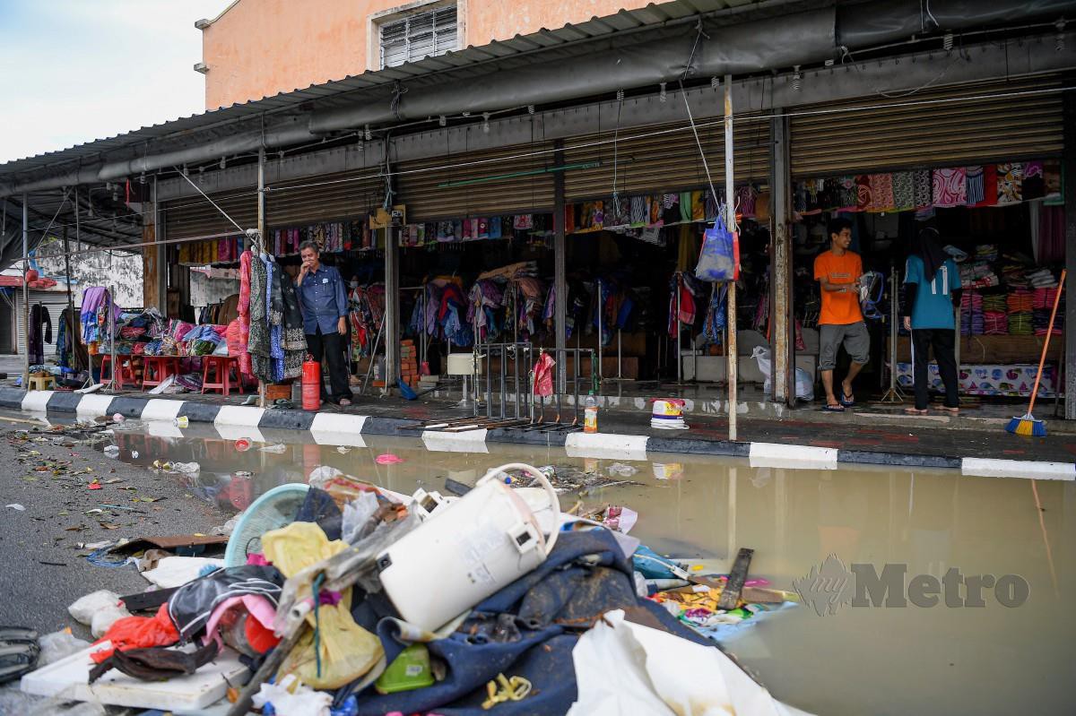 PEMILIK premis perniagaan sekitar Bandar Kota Tinggi mula membersihkan kedai masing-masing selepas banjir mula surut. FOTO BERNAMA