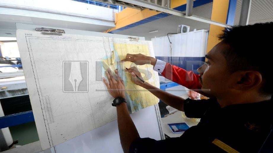 PEGAWAI Maritim Malaysia Pulau Pinang melihat peta lokasi seorang penumpang dipercayai terjatuh. FOTO Shahnaz Fazlie Shahrizal