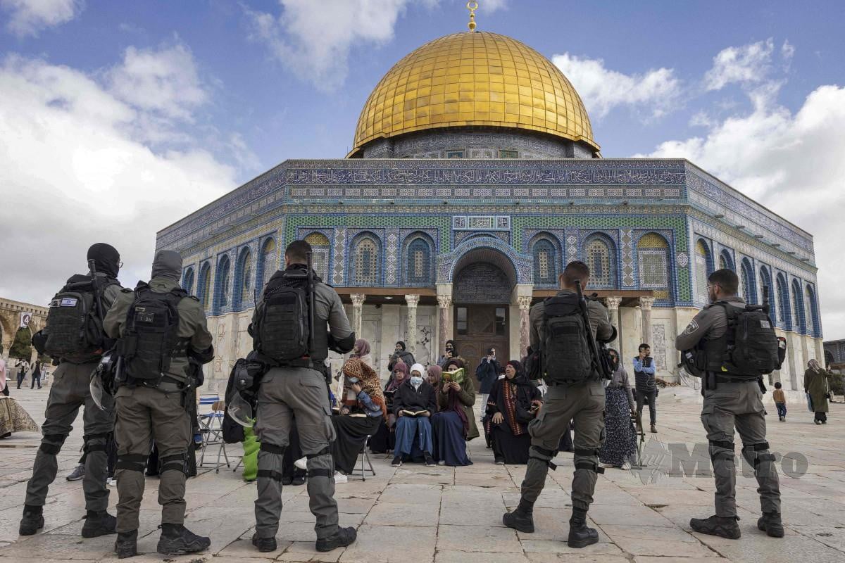 POLIS Israel berjaga di hadapan wanita muslim sedang membaca al-Quran di Masjd Al-Aqsa. FOTO AFP