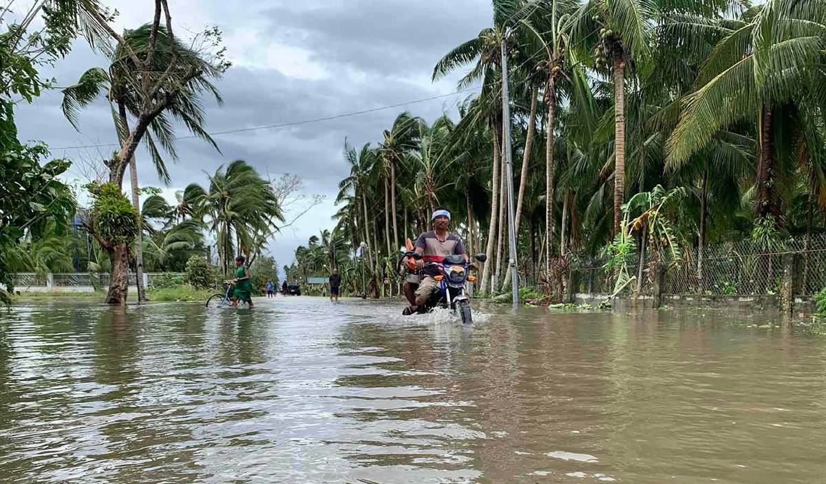 PENDUDUK meredah banjir dengan motosikal selepas taufan Malove membadai bandar Pola, Wilayah Oriental Mindoro, Filipina. FOTO AFP
