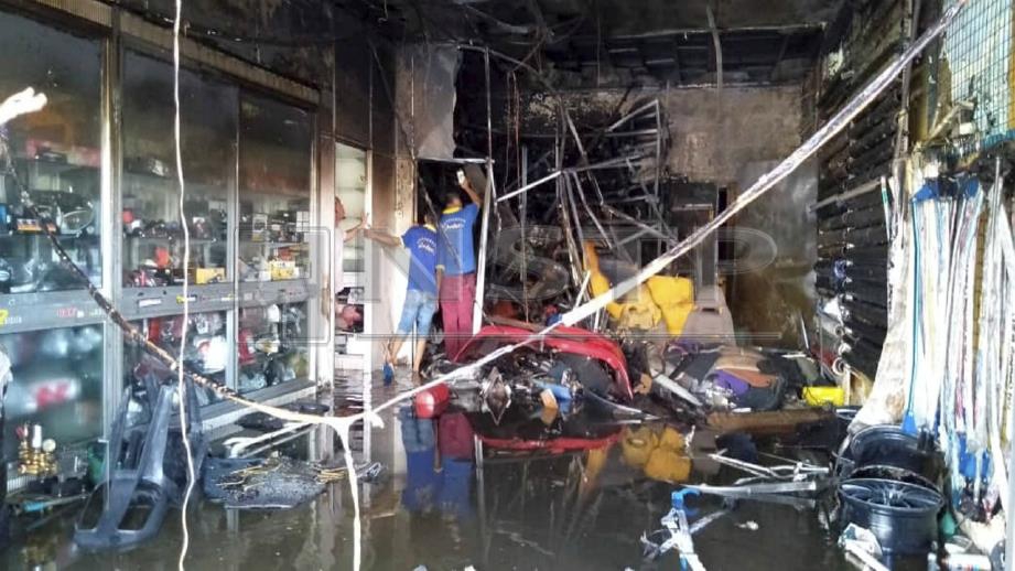 Pekerja kedai meninjau premis itu selepas api berjaya dipadamkan bomba. FOTO Nik Abdullah Nik Omar.