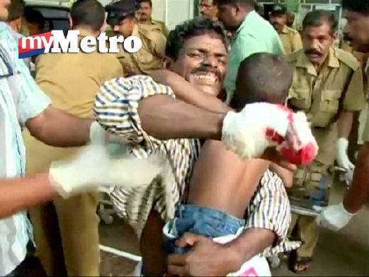Imej daripada rakaman video menunjukkan seorang lelaki yang cedera mendukung anaknya sebelum mendapatkan rawatan di hospital dalam kejadian kebakaran di kuil Puttingal Devi, Selatan India, awal pagi tadi. Reuters 