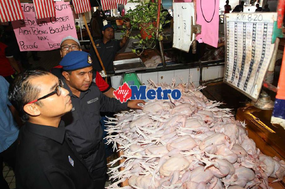 Mohamad Fitri (kiri) bersama pegawainya melihat tanda harga ayam sewaktu mengadakan pemeriksaan Skim Kawalan Harga Bulan Ramadan di Pasar Besar Alor Setar. FOTO Sharul Hafiz Zam 
