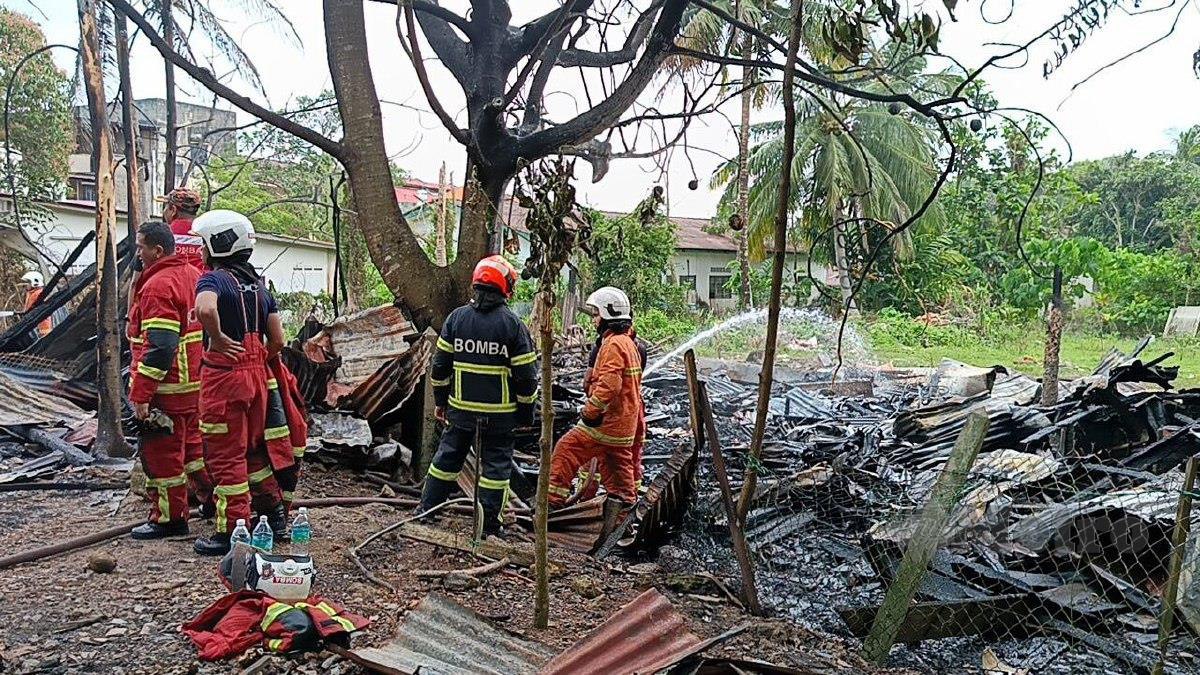 ANGGOTA bomba memadam sisa bara di kedua-dua rumah mangsa di Lorong Zakaria, Jalan Alor Gajah, yang musnah terbakar hari ini. FOTO Meor Riduwan Meor Ahmad.