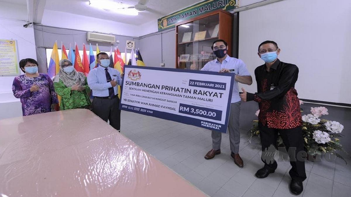 Wan Ahmad Fayhsal (dua dari kanan) menyerahkan replika cek kepada Abd Samad (kanan) di SMK Taman Maluri. FOTO ihsan Pejabat Timbalan Menteri Belia dan Sukan.