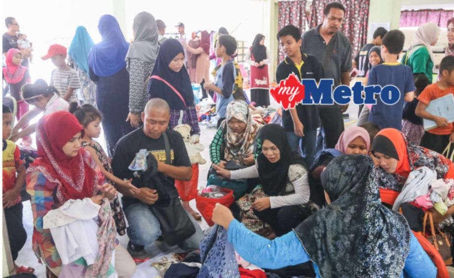 Pengunjung 'Free Market Kembali Ke Sekolah' memilih pakaian seragam dan juga barangan lain yang diperoleh percuma di Surau As Syakirin Precint 14, Putrajaya. FOTO Fariz Iswadi Ismail 