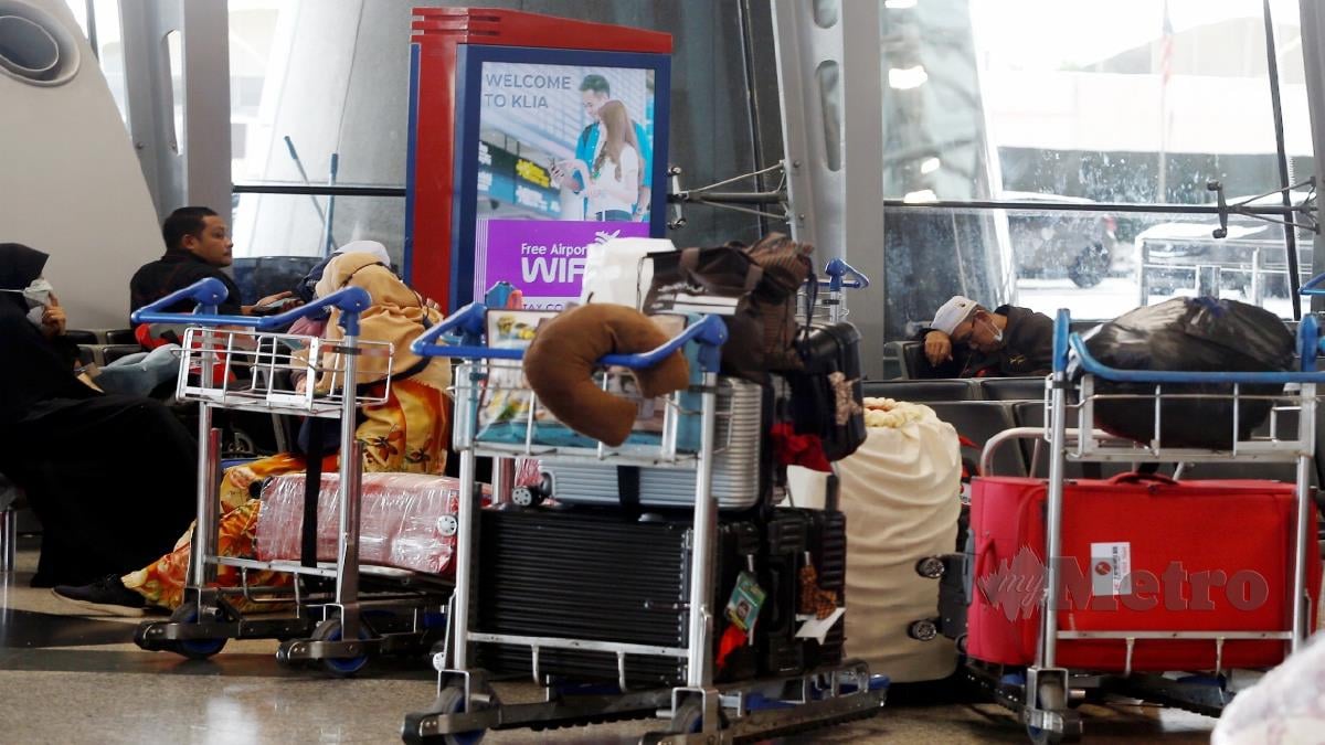 ANGGOTA keselamatan KLIA membantu sebahagian bakal jemaah haji yang terkandas di ruang legar Lapangan Terbang Antarabangsa Kuala Lumpur (KLIA), Sepang. FOTO HAIRUL ANUAR RAHIM