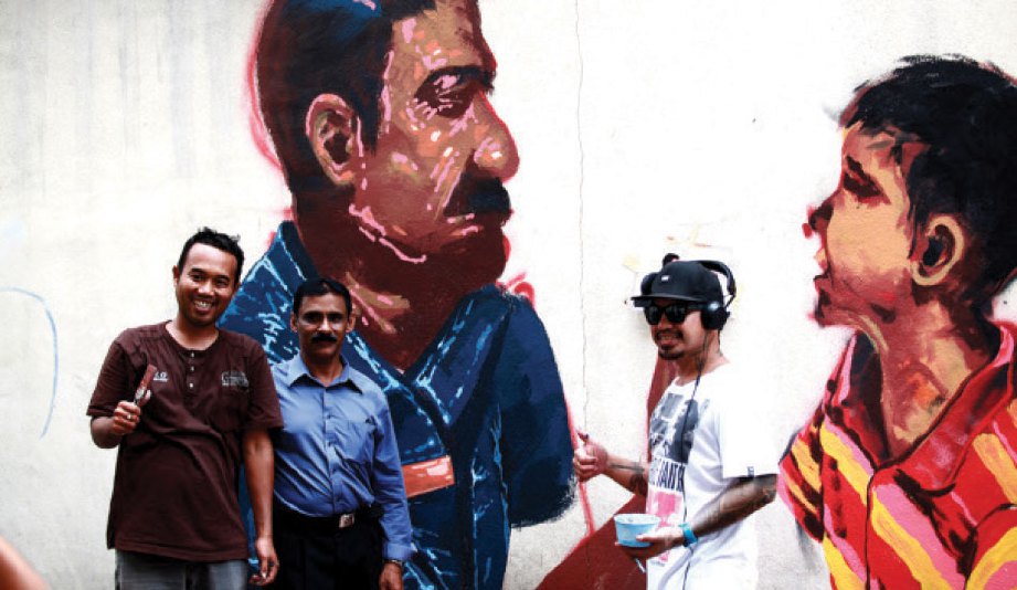 WAJAH Sarjan Mejar Krishna Moorthy (tengah) yang bertugas di Balai Polis Chow Kit turut diabadikan oleh artis Andi Ramdani (kiri) dan Tristram Miravalles (kanan).