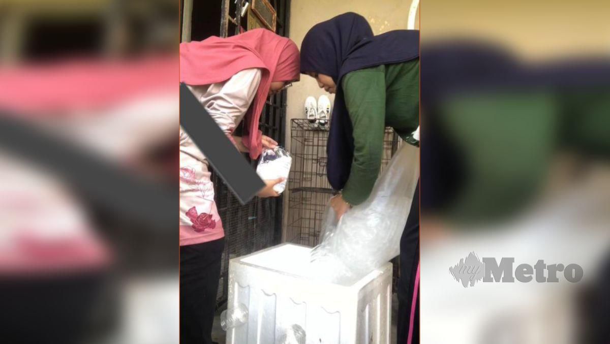 AINUR (kanan) bersama adiknya memasukkan ais dalam kotak gabus. FOTO ihsan Ainur Aliea Abdullah
