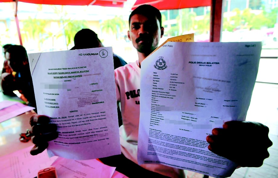 Mohd Ruslan menunjukkan salinan laporan polis dan surat perintah mahkamah.
