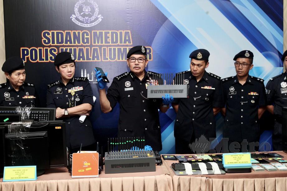 MAZLAN bersama barang rampasan serbuan di dua buah premis kegiatan penipuan atas talian di sekitar Bukit Bintang. FOTO AMIRUDIN SAHIB.
