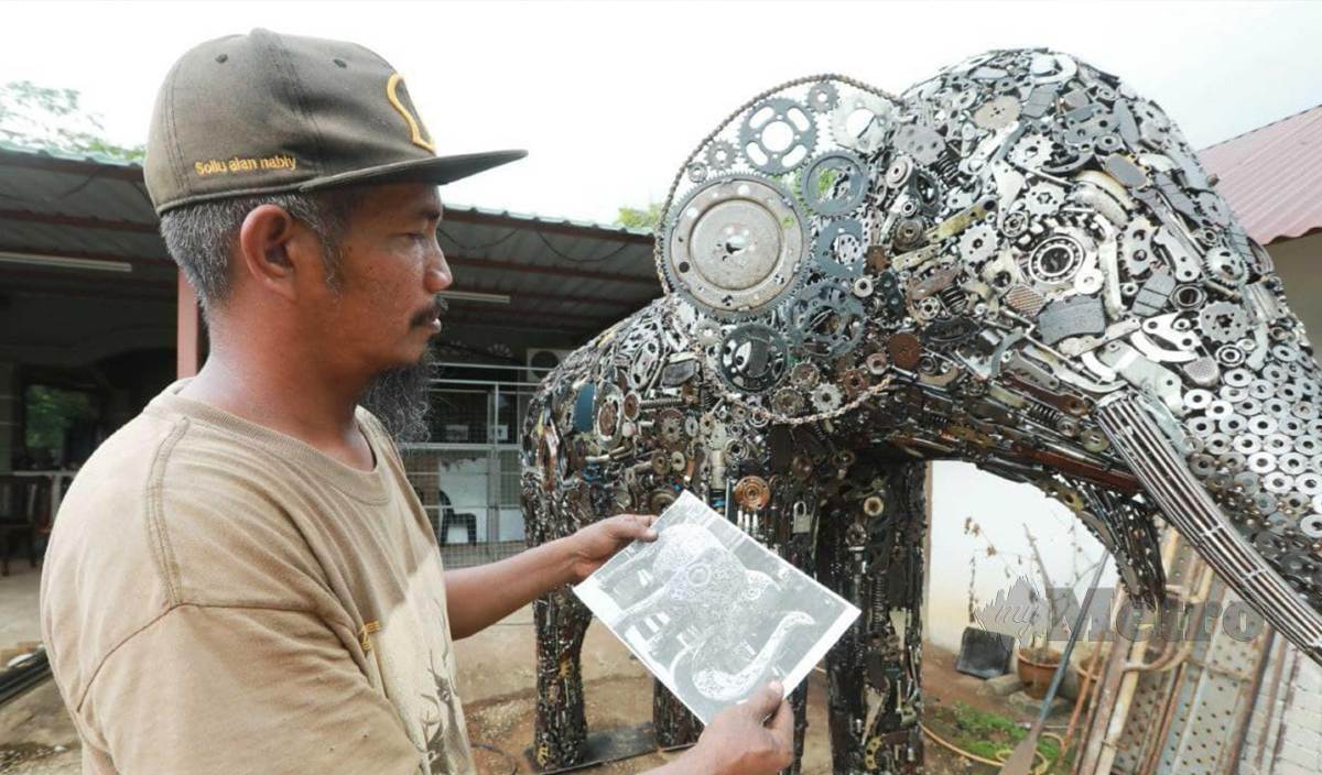 MOHD Norazly melihat gambar sebagai panduan untuk menghasilkan replika gajah besi yang pertama di Pahang. FOTO Mohd Rafi Mamat 