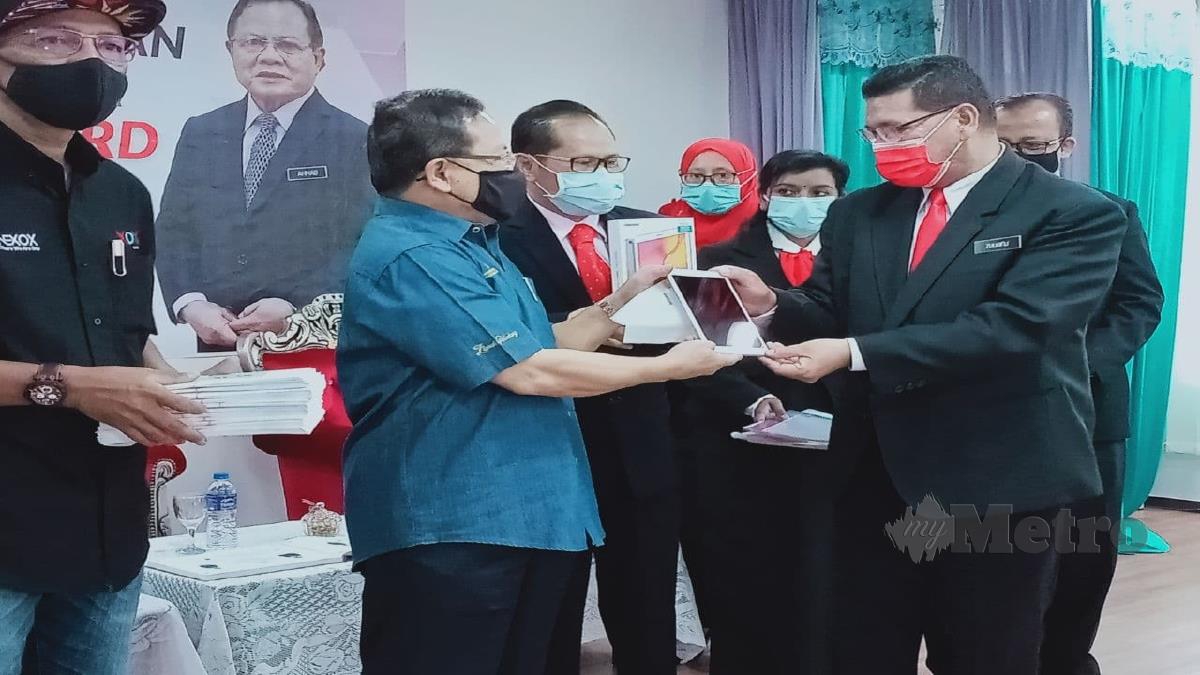 AHMAD (kiri) menyampaikan peranti pintar kepada pengetua dalam Parlimen Jasin sambil diperhatikan Pengarah Pendidikan Melaka, Dr Mohd Azam Ahmad (tengah). FOTO Amir Mamat.