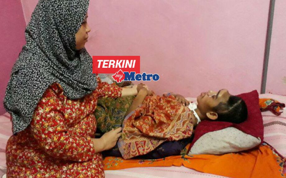 Siti Hapisah sentiasa memberi tumpuan kepada Muhamad Syazwan yang terlantar di rumah selepas terbabit dalam kemalangan. FOTO Azahar Hashim 