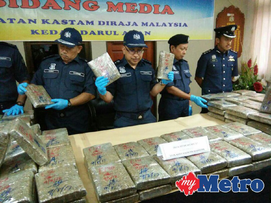 Johari  (tengah) menunjukkan sebahagian daripada 200 ketulan ganja mampat seberat 198.45 kg bernilai RM396,900 yang ditemui dalam sebuah kereta Preve yang dipandu seorang lelaki di Kompleks KIK Bukit Kayu Hitam, Rabu lalu. FOTO Zuliaty Zulkiffli