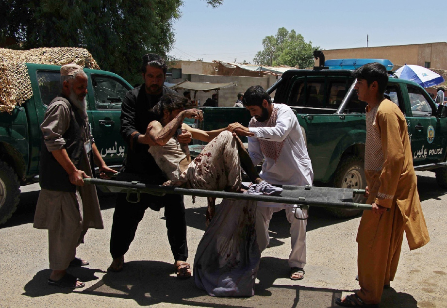 Orang ramai membantu mangsa yang cedera akibat serangan bom depan sebuah bank di bandar Lashkar Gah, Afghanistan, hari ini. - Foto AFP