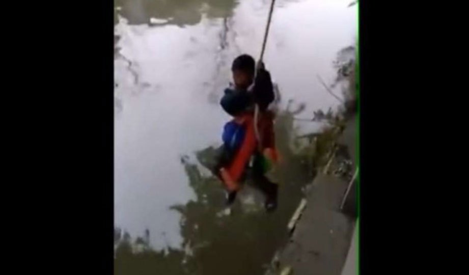 SEDUTAN video  menunjukkan seorang budak lelaki digantung di atas sungai oleh bapanya kerana tidak menyiapkan kerja sekolah. - Agensi