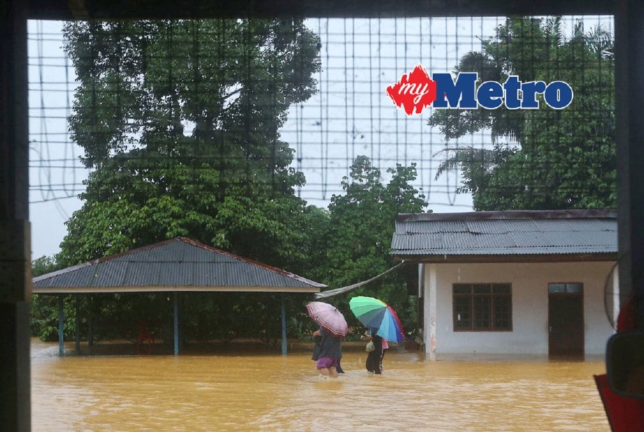 Sebahagian penduduk meredah banjir di Kampung Bukit Gemuruh. FOTO GHAZALI KORI