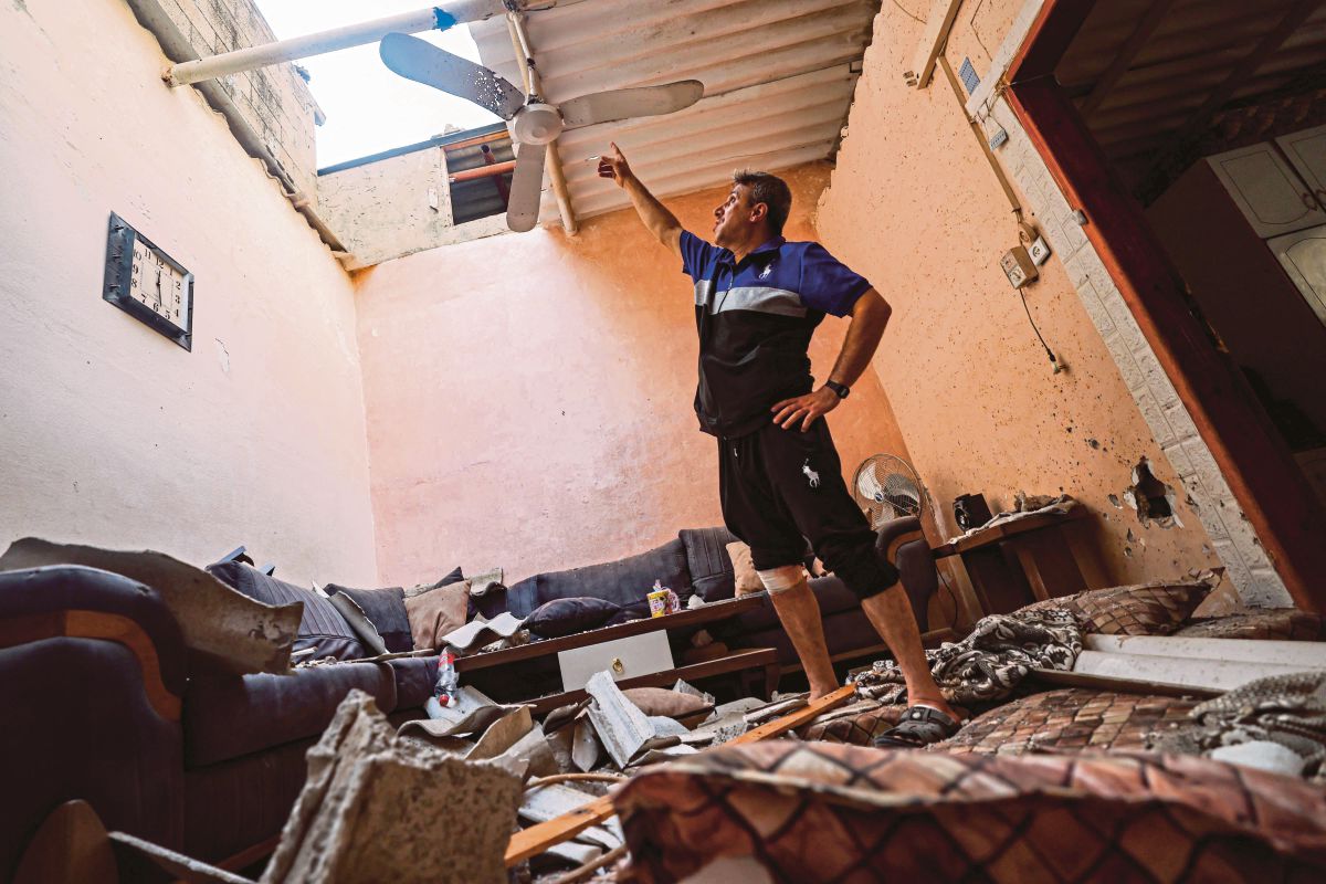 LELAKI memeriksa kerosakan di sebuah rumah akibat serangan Israel di Semenanjung Gaza. FOTO AFP 