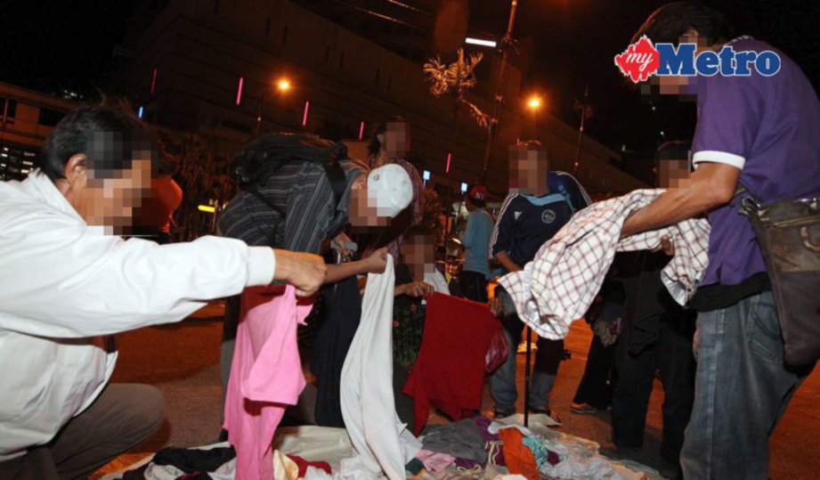 GELANDANGAN memilih pakaian yang  disumbangkan NGO kepada mereka. FOTO Mohd Azren Jamaludin 